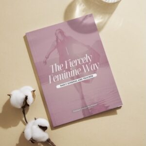 Journal on a desk besides a glass of water and some flowers